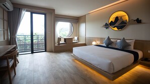 Habitación de hotel con una cama grande, un escritorio, una silla, una ventana con vistas y una obra de arte en la pared.