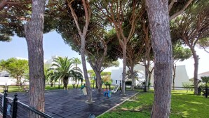 Un parque con árboles, un área de juegos y una zona pavimentada.