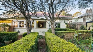 A house with a well-maintained garden, a visible front door, and a window with a view of the interior. - Secret Garden Cottage (Katoomba)