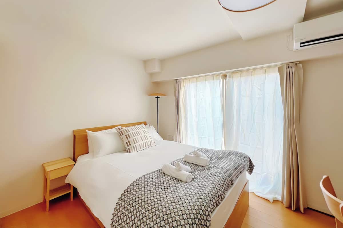 Une chambre d’hôtel avec un lit, une table de chevet, une lampe et une fenêtre avec des rideaux.