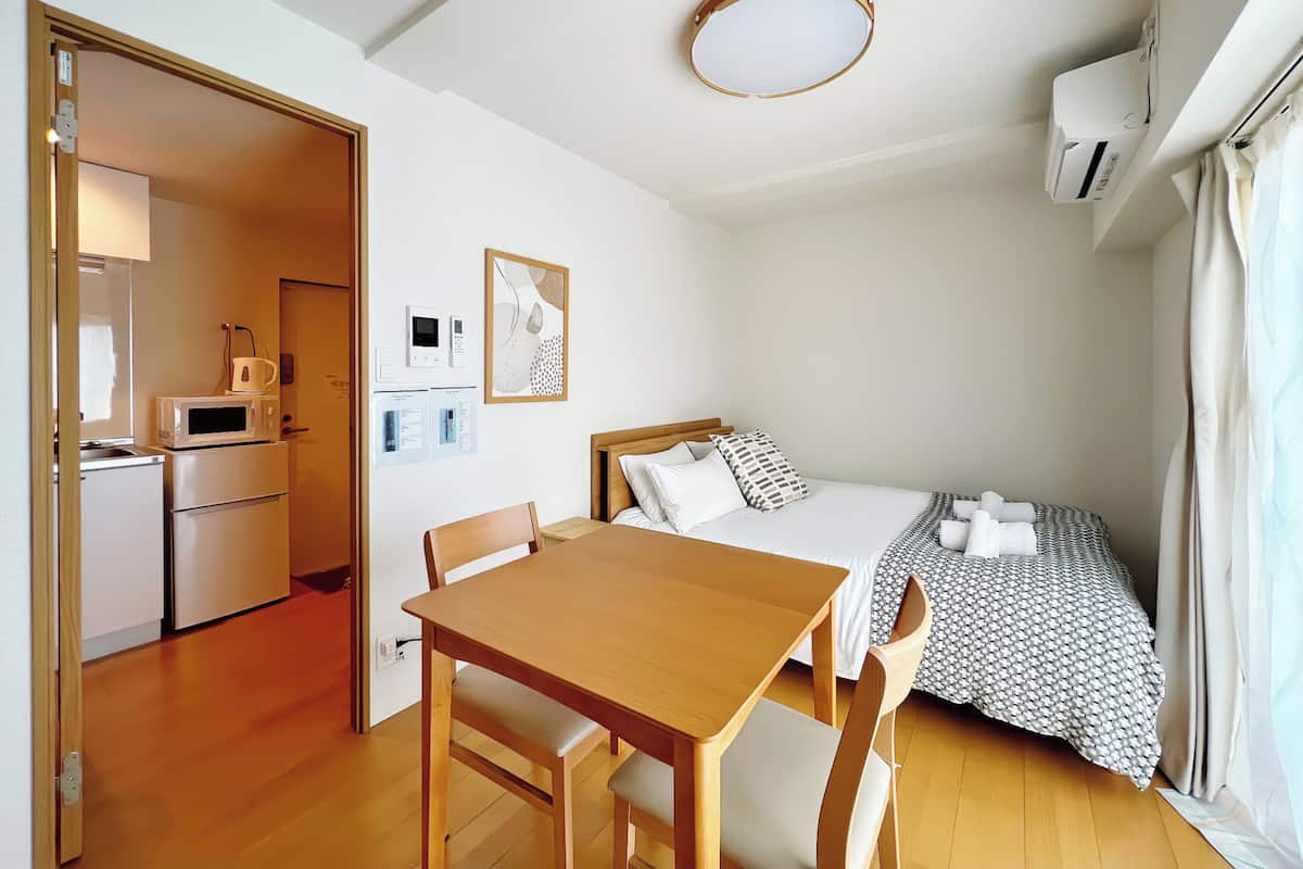 Une chambre à coucher de taille réduite, comprenant un lit, une table de chevet et un petit espace bureau.