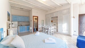A bedroom with a bed, pillows, a bedside table, a desk, and a chair. There is a bathroom with a toilet and sink. - Chic Villa Antonina Studio no2167 (Marinella)