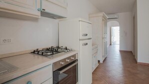 Una cocina con estufa a gas, horno y refrigerador blanco.