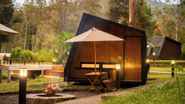 Un allotjament modern d'estil rústic de cabana, amb zona de menjador, espai exterior per seure i una llar de foc.