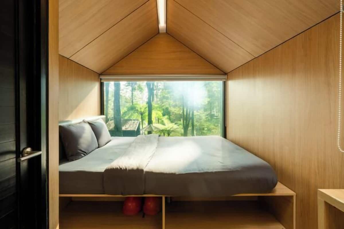 A bedroom with a bed, a window, and a view of trees.