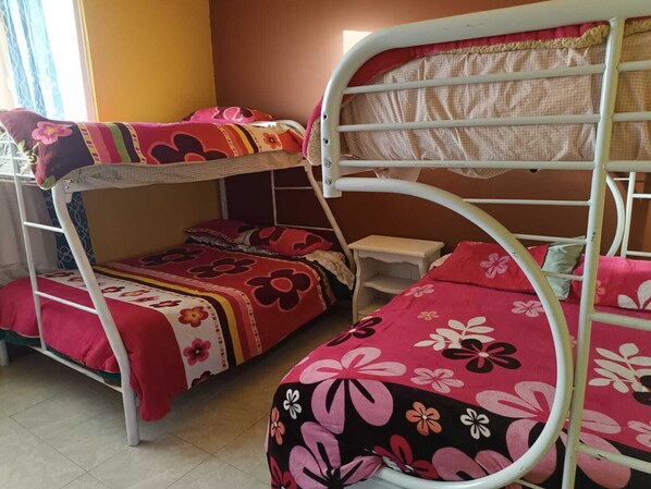 A bunk bed room with two beds, each with floral bedding. There is a small bedside table on the lower bunk.