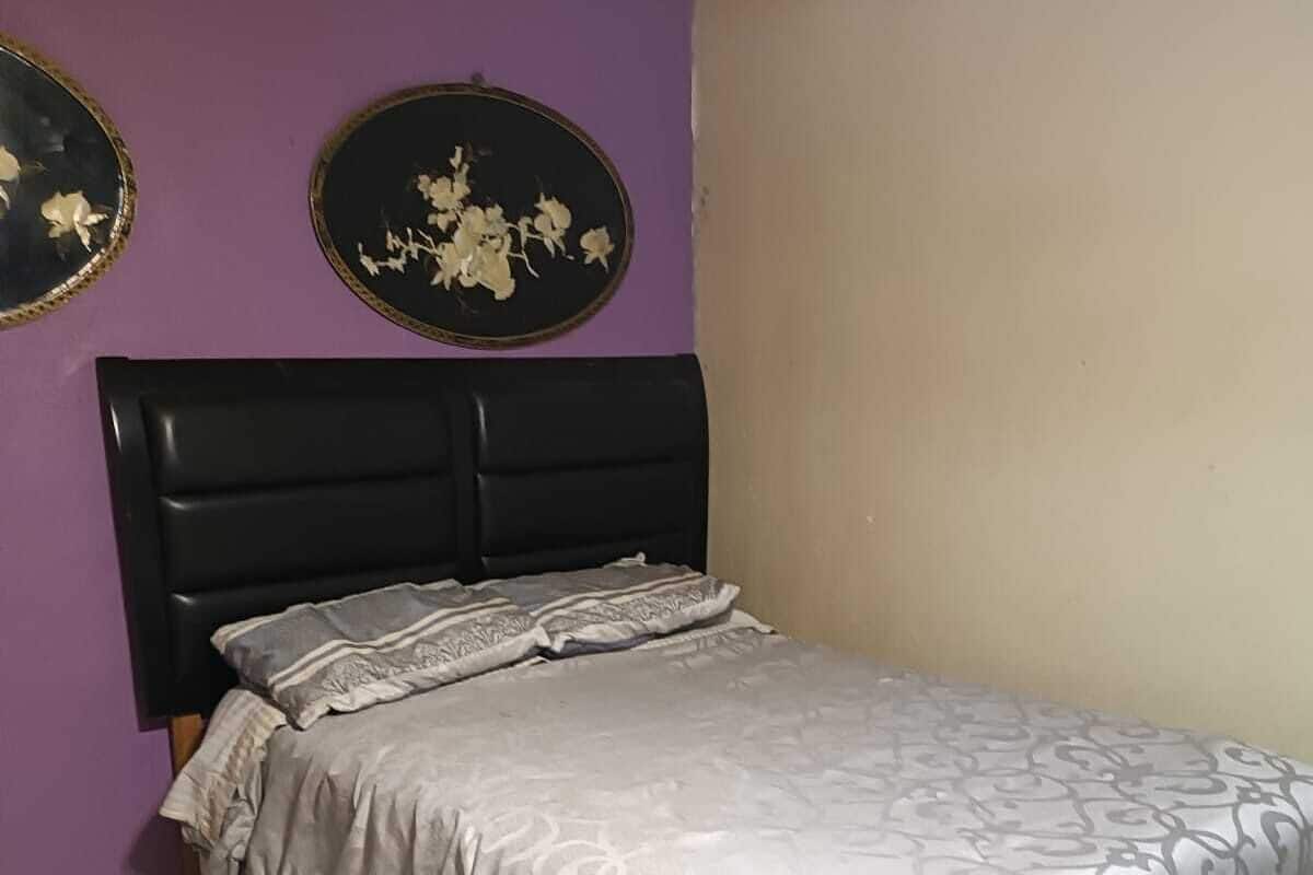 A single bed with a headboard, a patterned bedspread, and two wall-mounted decorative plates with floral designs.