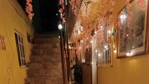 A staircase with stone steps and a handrail, decorated with hanging pink flowers and string lights. - HOSPEDAJE BARATO MI CASITA DE COLORES (Tijuana)