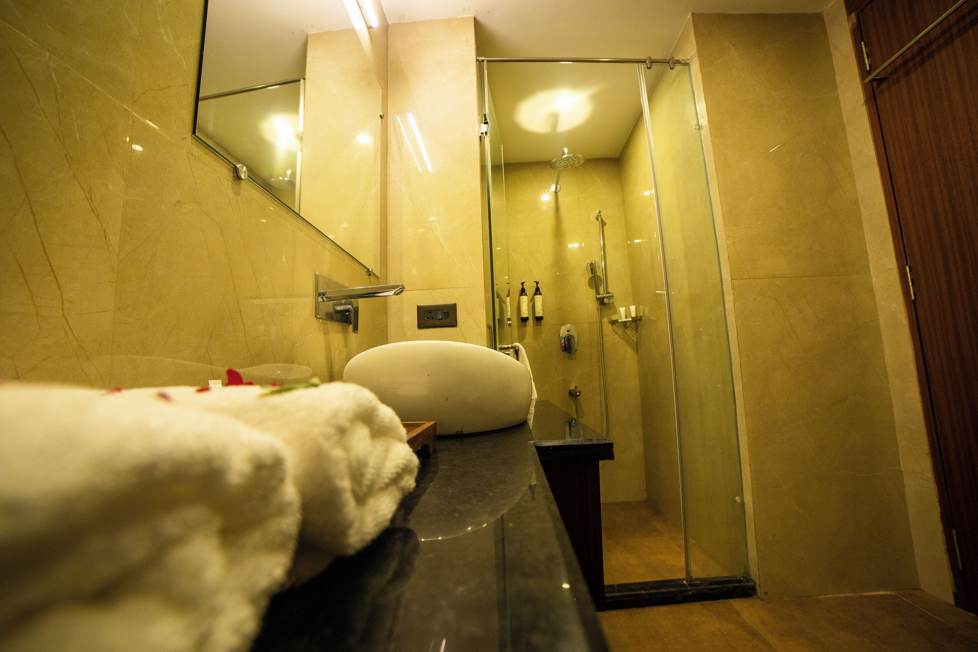 A bathroom with a glass shower enclosure, a white sink, and a mirror above the sink.