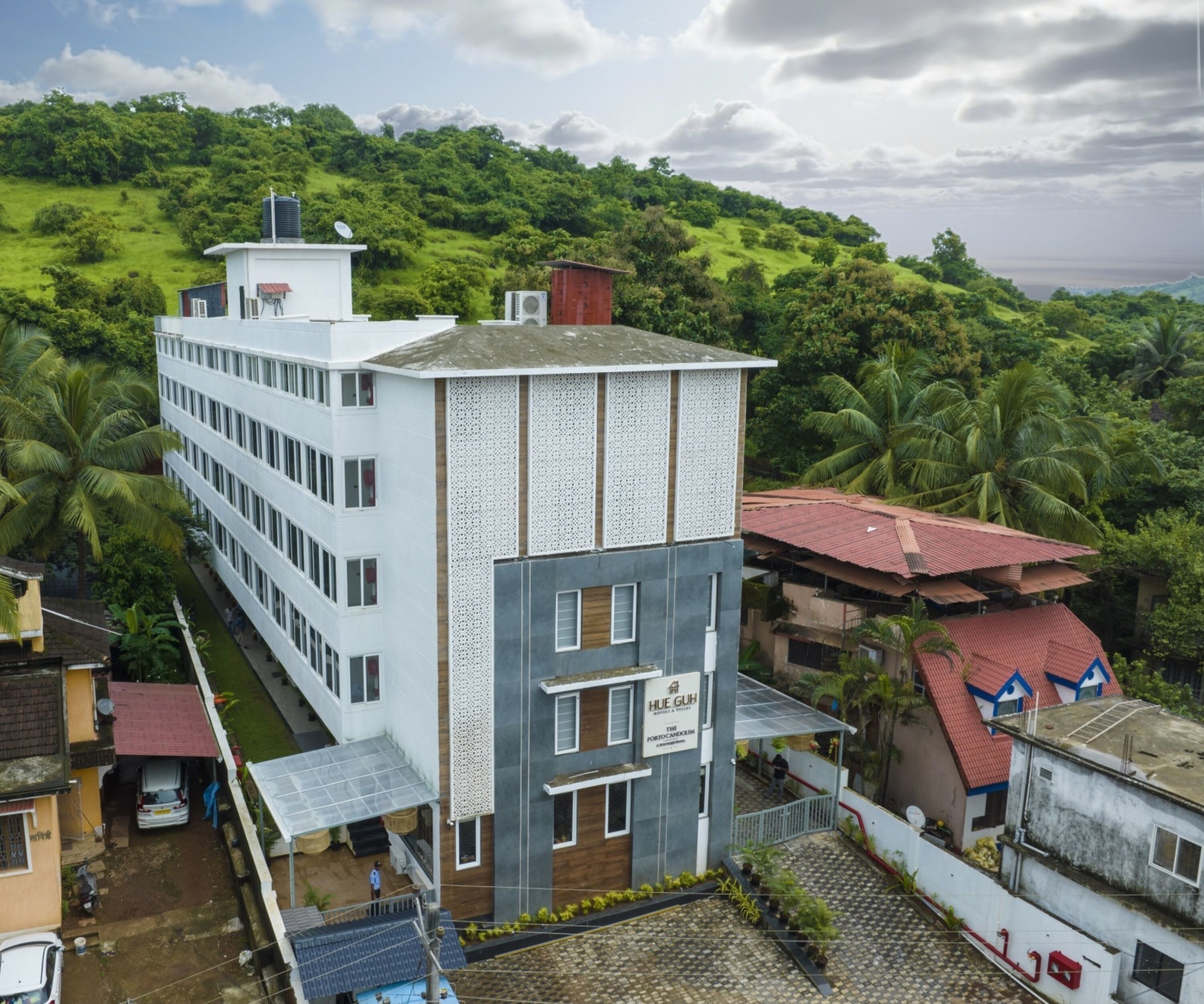 A multi-story building with a flat roof, surrounded by lush greenery.