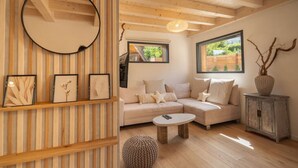 A modern living room with a wooden ceiling, a round mirror, a sofa, a coffee table, and a cabinet.