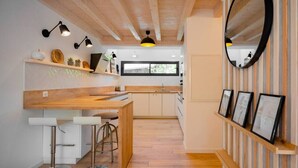 A modern kitchen with wooden beams, a central island, bar stools, and pendant lighting.