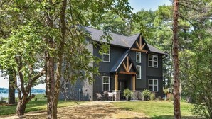 A two-story house with a dark exterior, a sloped roof, and a front porch with wooden beams. - New lake Retreat 1.5 hours from Twin cities in the heart of WI cabin country! (Frederic)