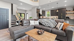 A modern living room with a grey sectional sofa, a wooden coffee table, and a staircase leading to an upper level. - New lake Retreat 1.5 hours from Twin cities in the heart of WI cabin country! (Frederic)