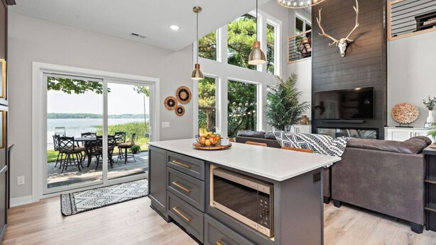 A modern kitchen with a large island, a dining area with outdoor seating, and a living room with a fireplace. - New lake Retreat 1.5 hours from Twin cities in the heart of WI cabin country! (Frederic)
