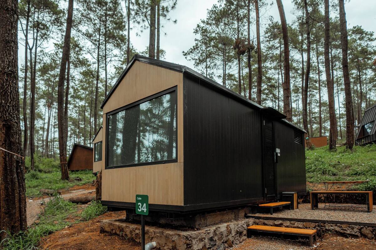 Uma cabana com uma janela grande, uma porta e uma placa com o número 34 no chão.