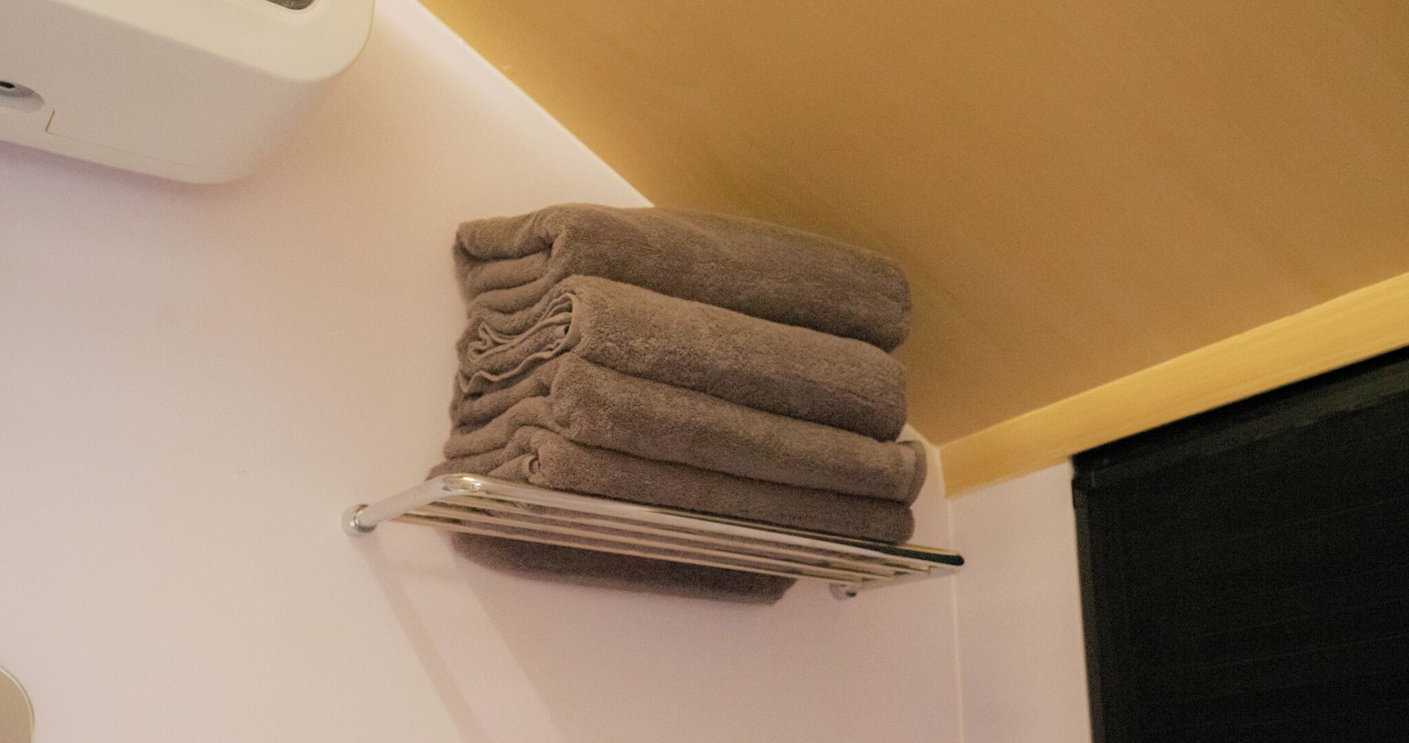 A towel rack with folded towels against a wall.