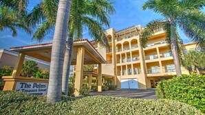 Ein Hotel mit Innenhof, Palmen und einem Schild mit der Aufschrift 'The Palms of Treasure Island'.