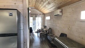 L’intérieur d’une cabane en bois comprend un coin repas, un réfrigérateur et un appareil de climatisation.