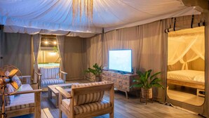 Una habitación acogedora con cama, televisor, ventilador y zona de estar.