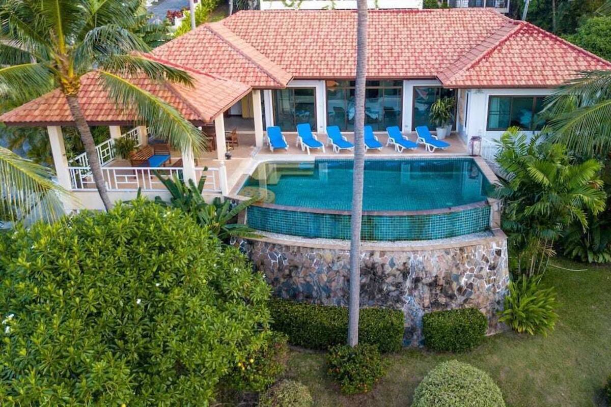 A resort with a swimming pool, lounge chairs, and tropical landscaping.