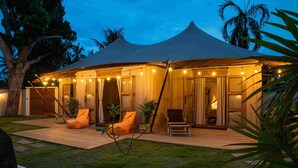 Un alojamiento con carpa, terraza de madera, asientos al aire libre y luces colgantes.