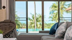 Una sala moderna con un amplio ventanal que da a una piscina y palmeras.