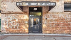 Der Eingang zum New Broughton Condominium mit einer Ziegelaußenwand und einer schwarzen Tür.