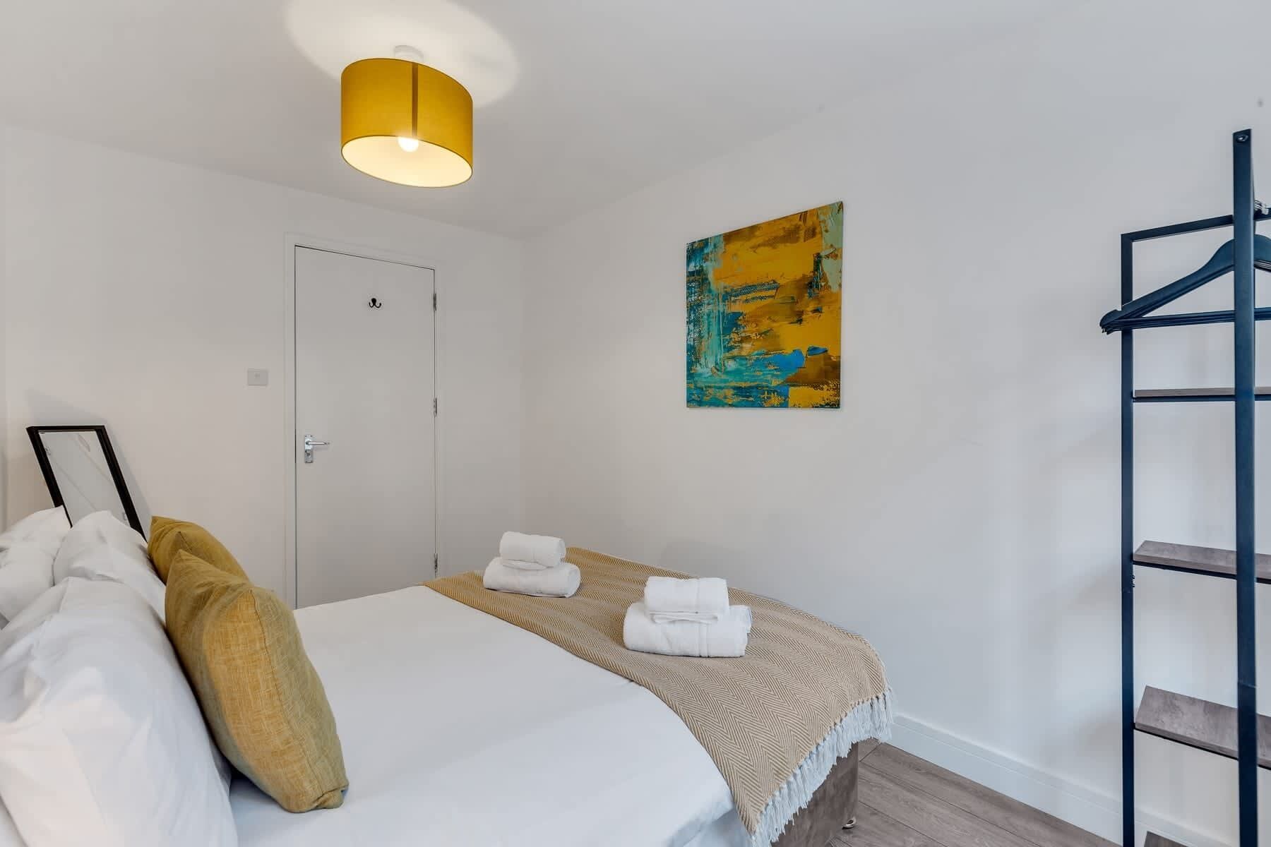 Une chambre à coucher avec un lit, un luminaire suspendu, une porte, un tableau et une armoire.