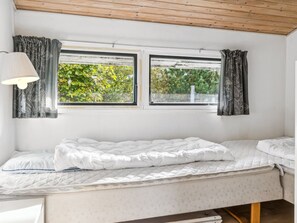 Cozy retreat with a single bed, white quilted mattress, and leaf-patterned curtains.