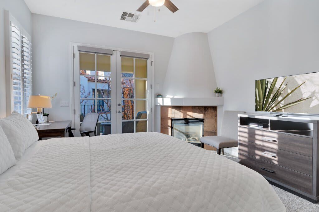 A bedroom with a large bed, a desk, a chair, a dresser, and a TV.
