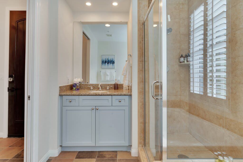 Une salle de bain avec une douche à parois de verre, un meuble-lavabo avec un plan de travail et un porte-serviettes.