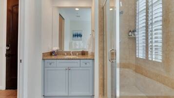 Une salle de bain avec une douche à parois de verre, un meuble-lavabo avec un plan de travail et un porte-serviettes.