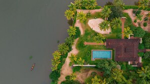 Eine Vogelperspektive eines tropischen Resorts mit Schwimmbad, einem großen Haus und Palmen.