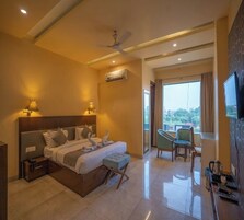 A hotel room with a bed, bedside tables, a desk, a chair, a television, and a balcony with a view.