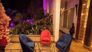 Un vestíbulo de hotel con dos sillones azules, una butaca roja y una mesa de centro de vidrio.