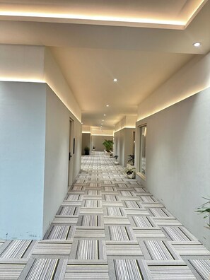 A modern hallway with patterned flooring, recessed lighting, and potted plants. - Grand 5 Resort (Meerut)