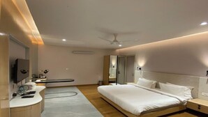 Una habitación de hotel moderna con una cama grande, una mesita de noche, un tocador con espejo y un ventilador de techo.