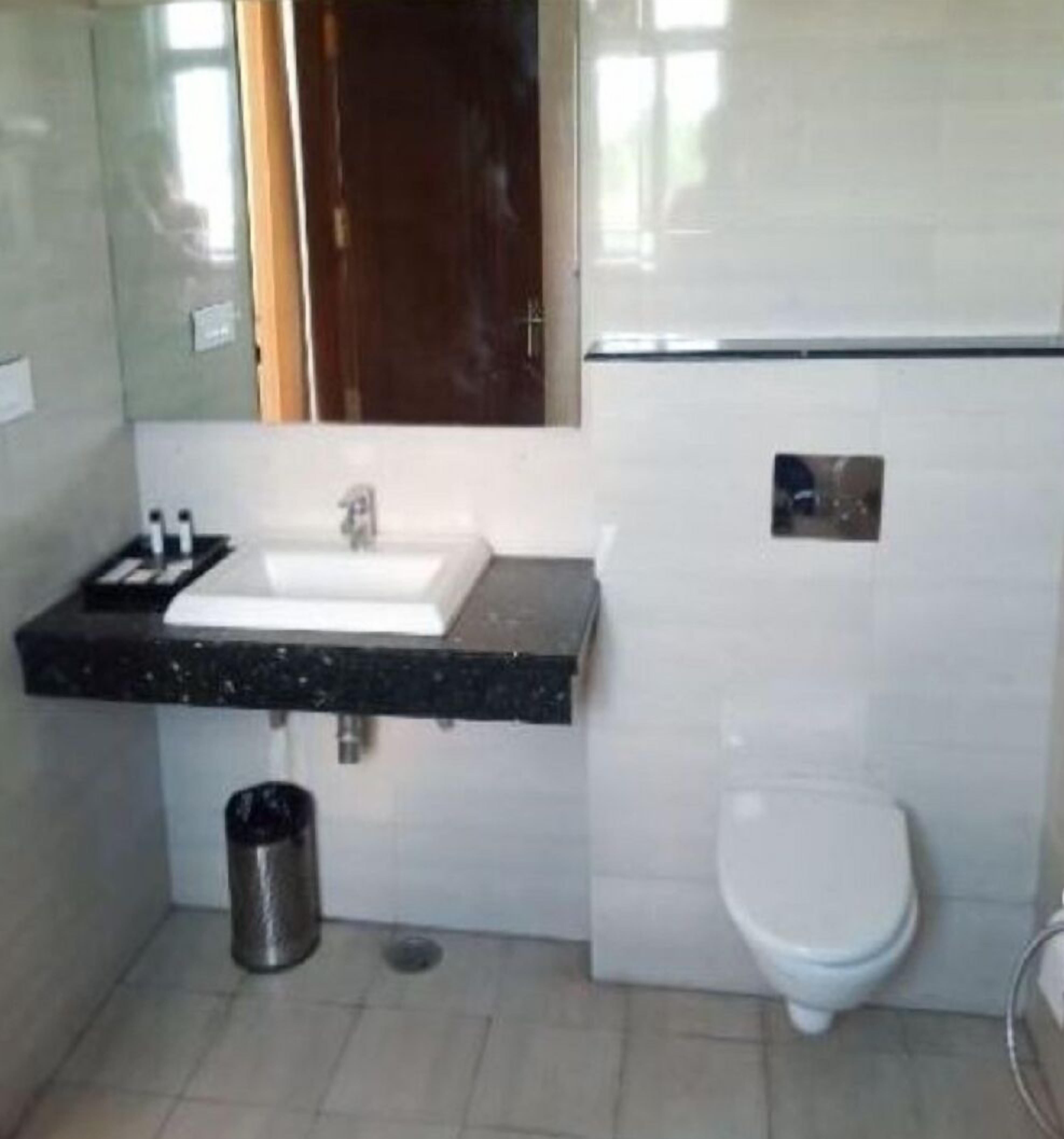 Une salle de bain avec un lavabo blanc, des toilettes et une poubelle.