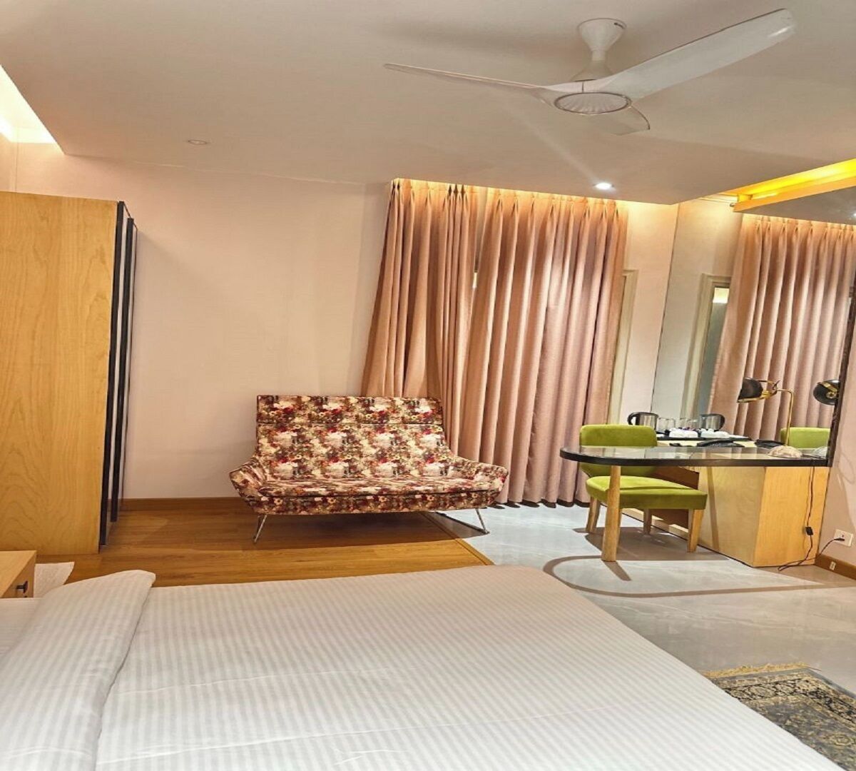A hotel room with a bed, a chair, a desk, and a mirror.