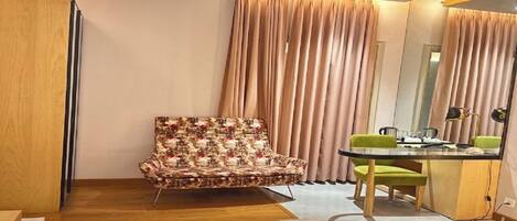 A hotel room with a bed, a chair, a desk, and a mirror.