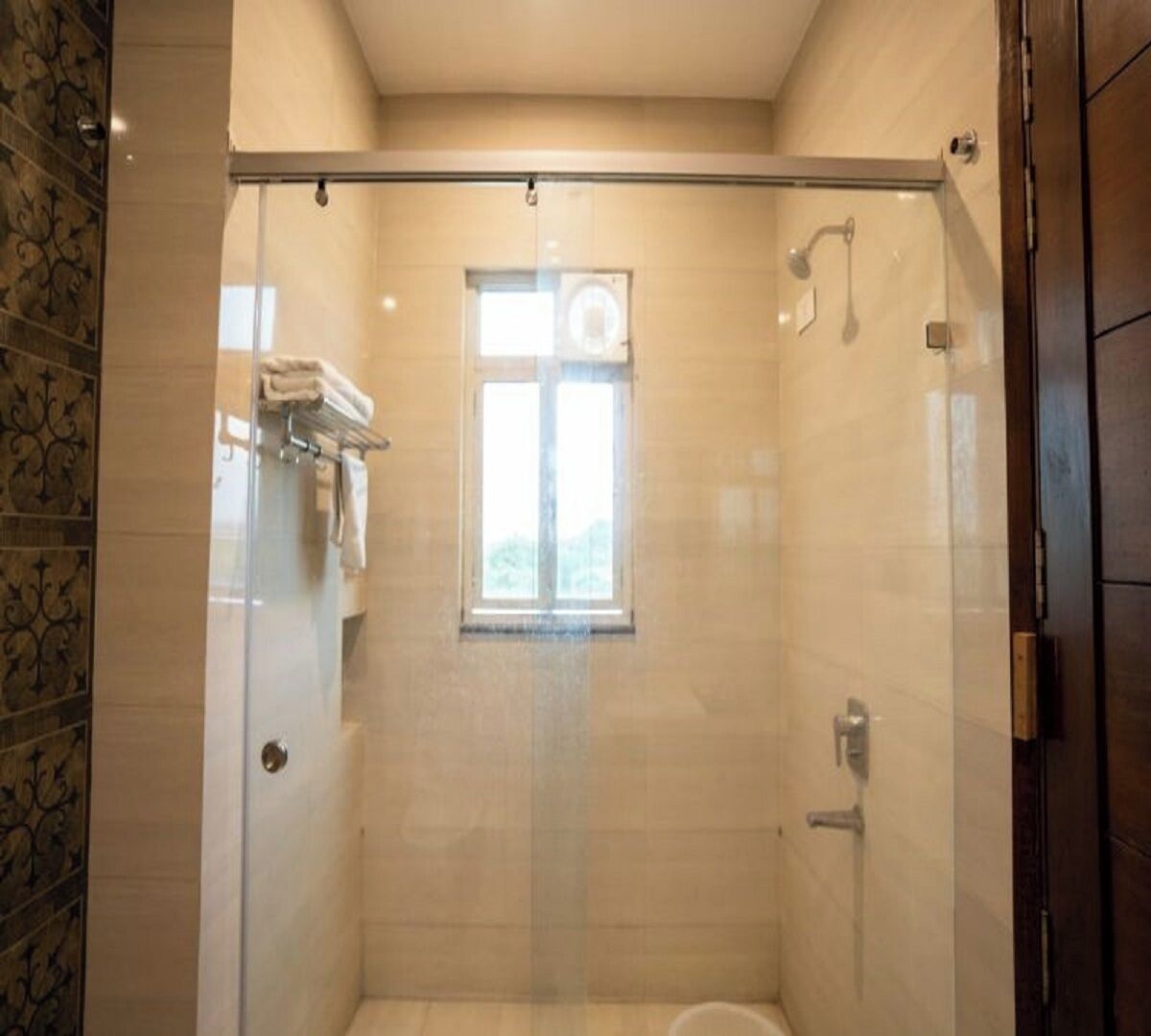 Une cabine de douche fermée par des parois en verre, dotée d’une fenêtre, d’un porte-serviettes et de toilettes.