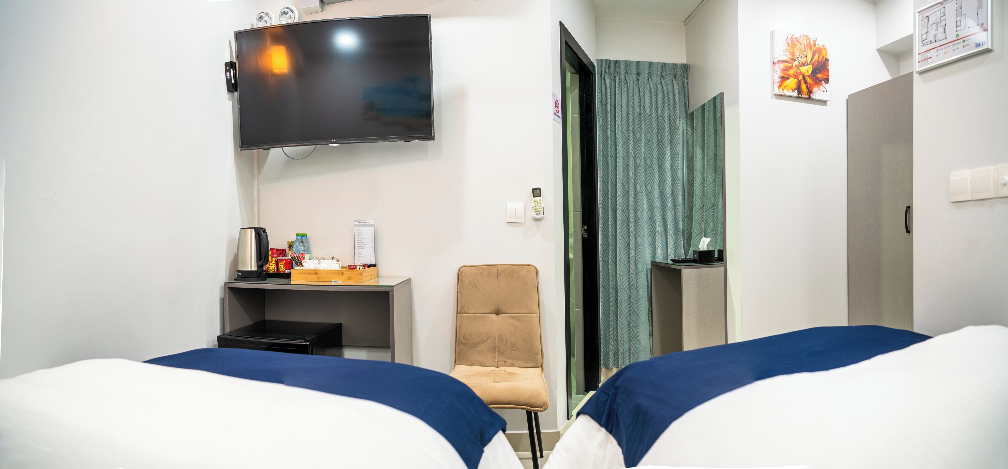 A hotel room with two beds, a TV, a desk with a chair, a small table, and a bathroom door.