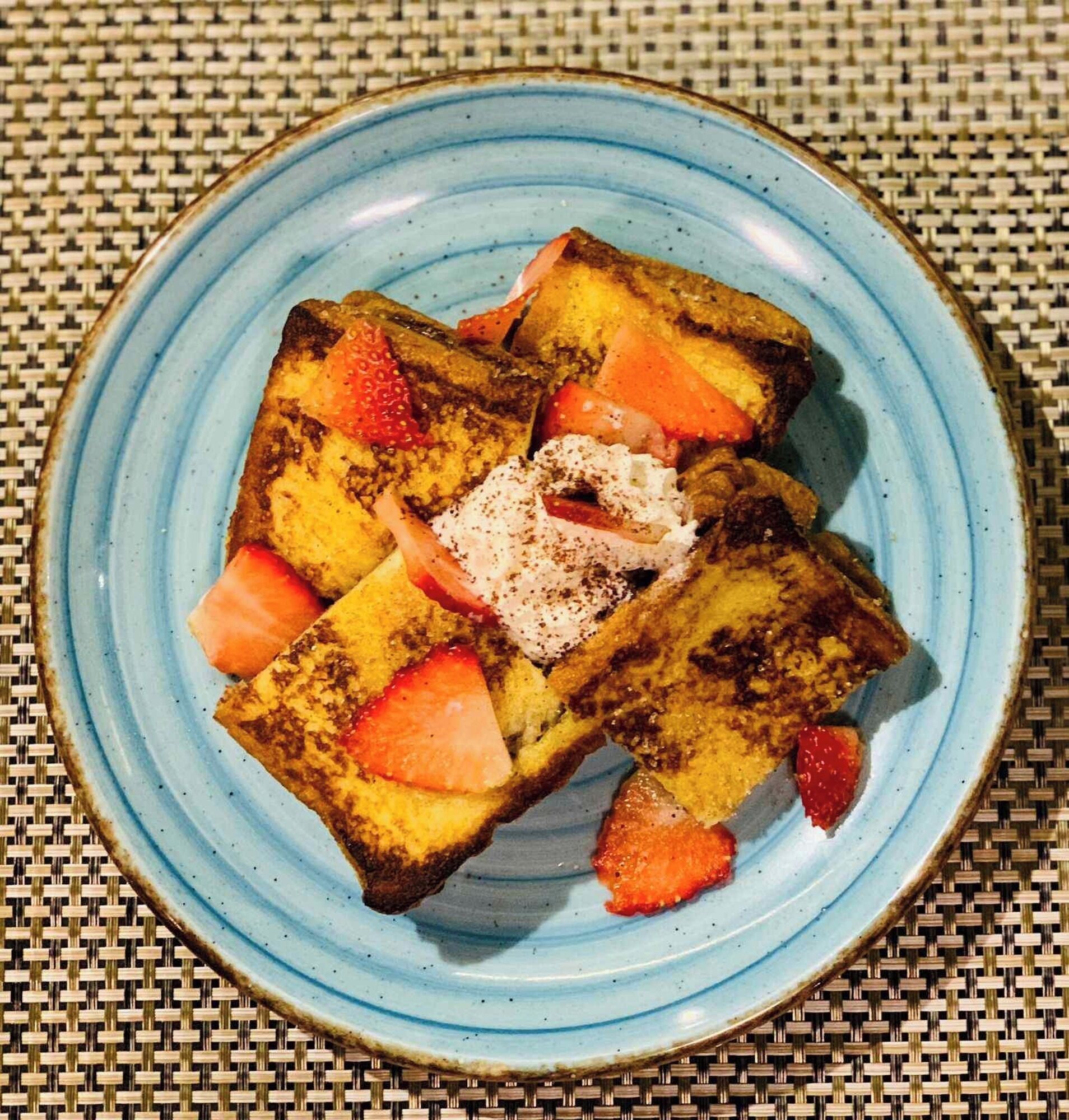 A plate with French toast, strawberries, and powdered sugar.