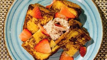 A plate with French toast, strawberries, and powdered sugar.
