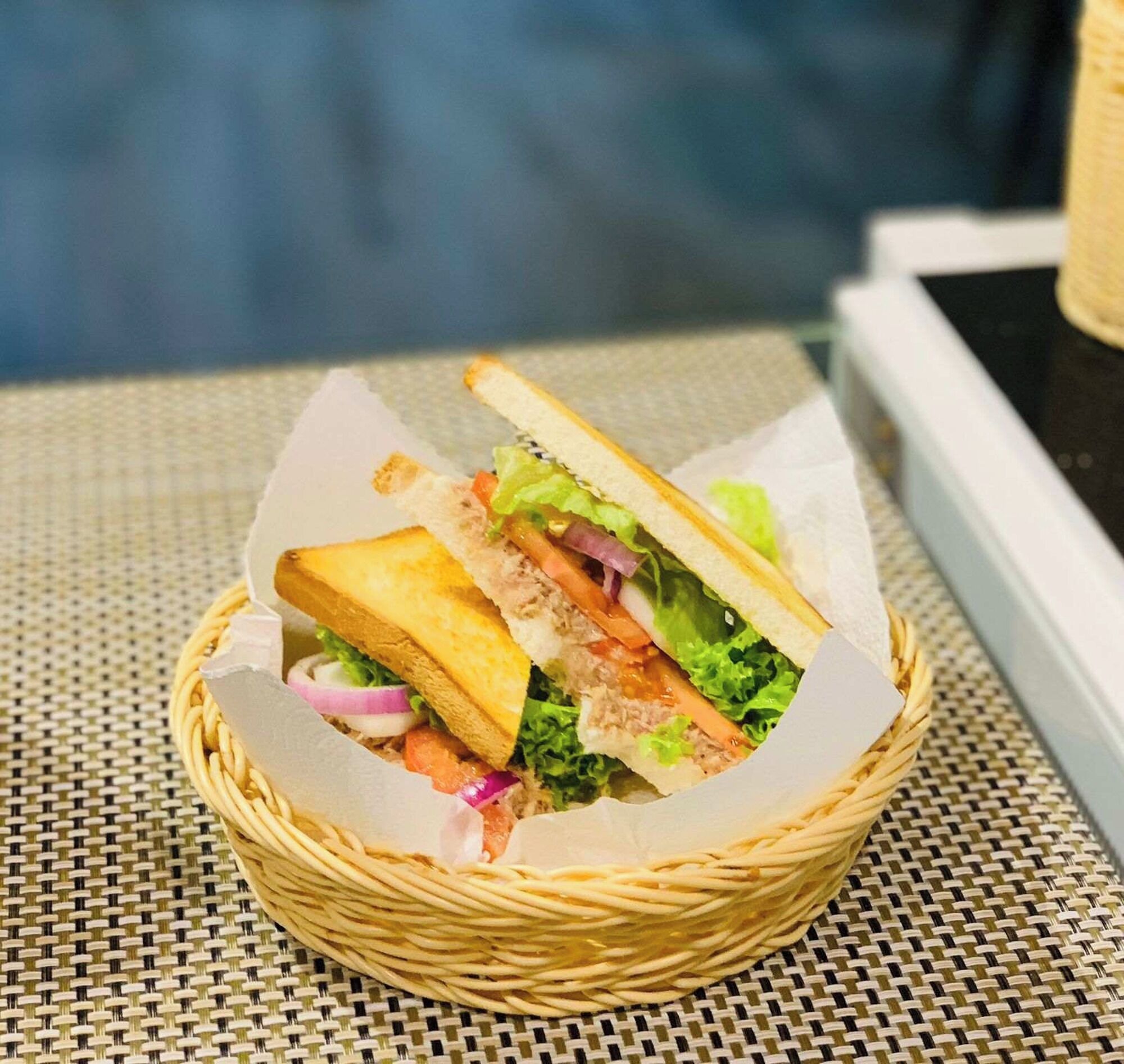 A sandwich in a woven basket on a table.