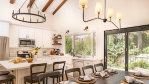 Une cuisine moderne avec des meubles blancs, un îlot central et un coin repas aménagé pour accueillir six personnes.