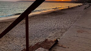 Une plage au coucher du soleil, une structure en bois et une promenade en béton.