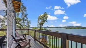A wooden deck with rocking chairs overlooking a lake. - Luxe at Lake Haven - Lakefront pool & hot tub (Sevierville)
