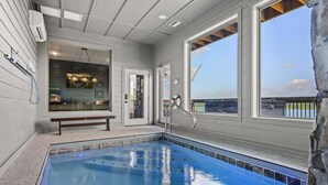 A swimming pool with a bench, a door, and large windows. - Luxe at Lake Haven - Lakefront pool & hot tub (Sevierville)